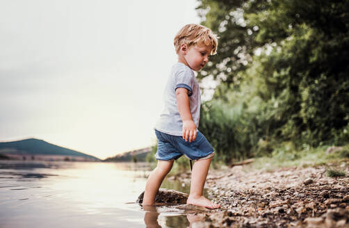 Ein nasses, kleines Kleinkind, das im Sommer barfuß an einem Fluss steht und spielt. - HPIF19265