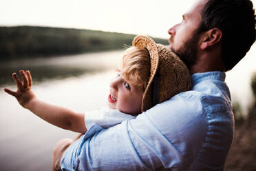 Ein erwachsener Vater mit einem kleinen Jungen im Sommer draußen am Fluss. - HPIF19278