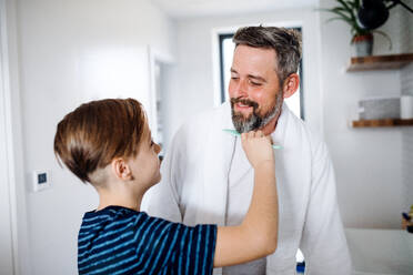A mature father with small son in the bathroom in the morning, combing hair. - HPIF19401