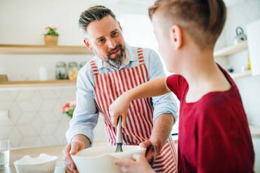 Ein reifer Vater mit seinem kleinen Sohn in der Küche, der Pfannkuchen macht. - HPIF19407
