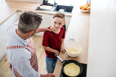 Blick von oben auf einen reifen Vater mit seinem kleinen Sohn in der Küche, der Pfannkuchen macht. - HPIF19416