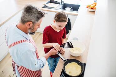 Blick von oben auf einen reifen Vater mit seinem kleinen Sohn in der Küche, der Pfannkuchen macht. - HPIF19417