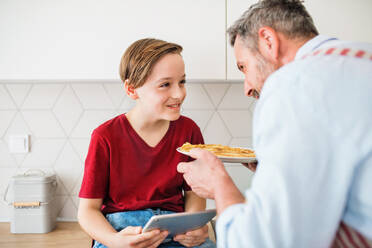 A mature father with small son indoors in kitchen, making pancakes. - HPIF19419