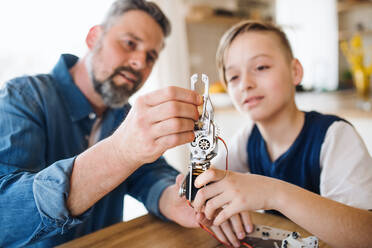 Ein reifer Vater mit seinem kleinen Sohn sitzt am Tisch in einem Haus und arbeitet an einem Schulprojekt. - HPIF19448