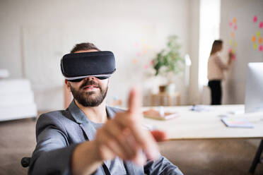 Zwei Geschäftsleute mit Rollstuhl im Büro arbeiten zusammen. Ein Mann trägt eine VR-Brille. - HPIF19507