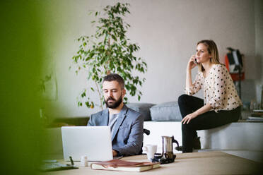 Zwei Geschäftsleute im Büro: ein Mann im Rollstuhl, der an einem Laptop arbeitet, und eine Frau, die ein Telefonat führt. - HPIF19520