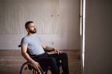 Hnadsome man in wheelchair looking out of the window. - HPIF19535