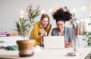 Junge kreative Frauen mit Laptop und Smartphone bei der Arbeit in einem Studio, Startup-Unternehmen. - HPIF19590