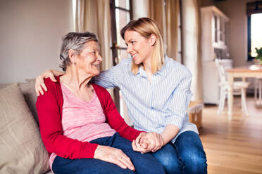 Portrait of an elderly grandmother with an adult granddaughter sitting on the sofa at home. Close up. - HPIF19620