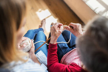 An unrecognizable elderly grandmother and adult granddaughter at home, knitting. Top view. - HPIF19628