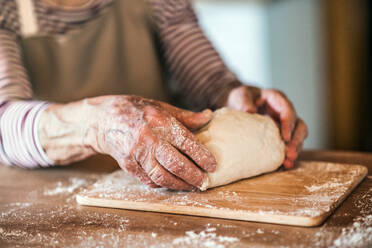 Hände einer nicht erkennbaren älteren Frau kneten Teig in der Küche zu Hause. - HPIF19645