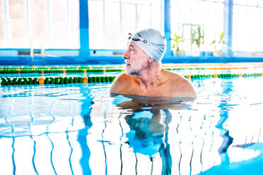 Älterer Mann im Wasser in einem Hallenbad, aktiver Rentner beim Sport. - HPIF19663