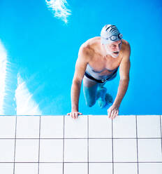 Älterer Mann, der in einem Hallenbad im Wasser steht. Aktiver Rentner beim Sport. Ansicht von oben. - HPIF19672