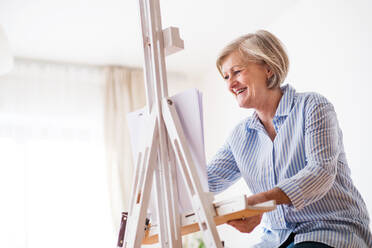 A happy senior woman painting at home. - HPIF19702