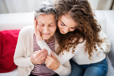 A teenage girl with grandmother at home, hugging. Family and generations concept. - HPIF19711