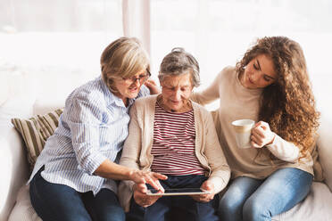 A teenage girl, her mother and grandmother with tablet at home. Family and generations concept. - HPIF19718