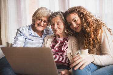 A teenage girl, her mother and grandmother with laptop at home. Family and generations concept. - HPIF19724