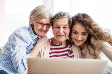 Ein Mädchen im Teenageralter, ihre Mutter und ihre Großmutter mit einem Tablet zu Hause - das Konzept der Familie und der Generationen. - HPIF19725