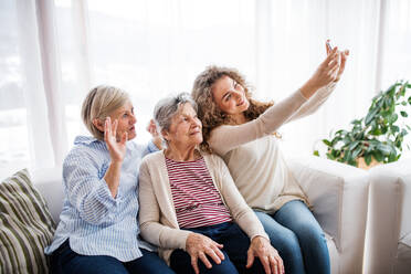 Drei Generationen von Frauen halten einen gemeinsamen Moment mit einem Selfie fest und zeigen so die Verbindung von Familie und Technologie - HPIF19732