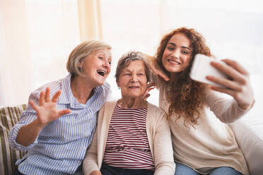 Drei Generationen von Frauen fangen einen gemeinsamen Moment mit einem Selfie ein, das die Familienbande und die moderne Technologie zeigt - HPIF19734