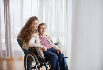 A teenage girl with grandmother at home, hugging. Family and generations concept. - HPIF19749