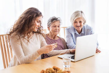 A teenage girl, her mother and grandmother with laptop at home. Family and generations concept. - HPIF19766