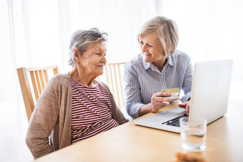 Ältere Frau mit ihrer Mutter mit Laptop zu Hause. Familie und Generationen Konzept. - HPIF19767