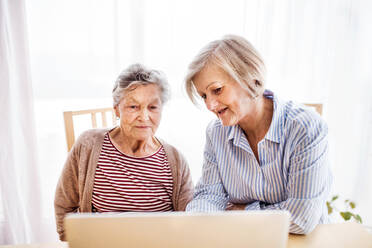 Ältere Frau mit ihrer Mutter mit Laptop zu Hause. Familie und Generationen Konzept. - HPIF19768