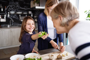 Ein kleines Mädchen mit ihrer Mutter und Großmutter zu Hause, beim Kochen. Familien- und Generationenkonzept. - HPIF19772