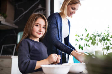 Ein kleines Mädchen, das mit seiner Mutter zu Hause kocht - ein Konzept für Familie und Generationen. - HPIF19774
