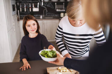 Ein kleines Mädchen mit ihrer Mutter und Großmutter zu Hause, beim Kochen. Familien- und Generationenkonzept. - HPIF19779