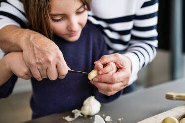 Ein kleines Mädchen mit ihrer nicht wiederzuerkennenden Großmutter, die zu Hause kocht - ein Konzept für Familie und Generationen. - HPIF19782