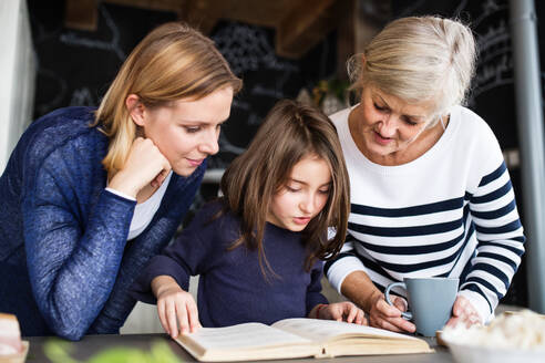 Ein kleines Mädchen mit seiner Mutter und seiner Großmutter zu Hause: das Konzept der Familie und der Generationen. - HPIF19787