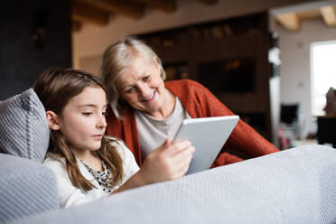Ein kleines Mädchen und ihre Großmutter mit einem Tablet zu Hause. Familien- und Generationenkonzept. - HPIF19814