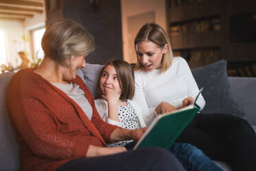 Ein kleines Mädchen mit seiner Mutter und seiner Großmutter zu Hause: das Konzept der Familie und der Generationen. - HPIF19817