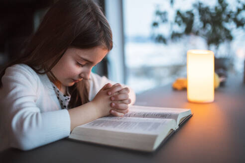 Ein kleines Mädchen mit Bibel zu Hause, das betet. - HPIF19840