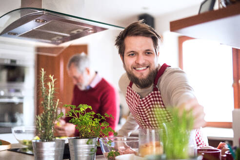 Hipster-Sohn mit seinem älteren Vater beim Kochen in der Küche. Zwei Generationen im Haus. - HPIF19847