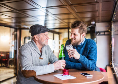 Ein älterer Vater und sein kleiner Sohn trinken Bier in einer Kneipe. - HPIF19901