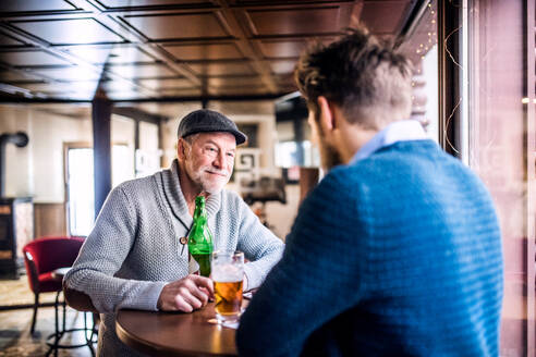 Ein älterer Vater und sein kleiner Sohn trinken Bier in einer Kneipe. - HPIF19903