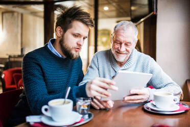 Senior father and his young son with tablet in a cafe. - HPIF19905