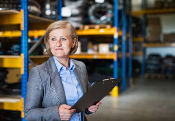 Portrait of a senior woman warehouse manager or supervisor with clipboard. Copy space. - HPIF19907