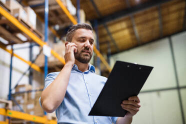 Warehouse worker or supervisor with a smartphone, making a phone call. - HPIF20019