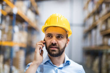 Warehouse worker or supervisor with a smartphone, making a phone call. - HPIF20021