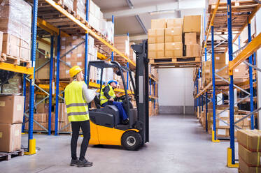 Young workers working together. Man forklift driver and a woman in a warehouse. - HPIF20066