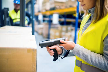 Unrecognizable warehouse woman worker or supervisor with barcode scanner. A mobile handheld PC with barcode scanner. - HPIF20068