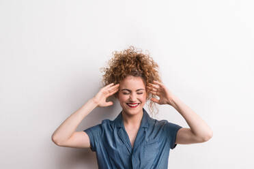 Young beautiful happy woman standing in studio, hands on temples. - HPIF20125