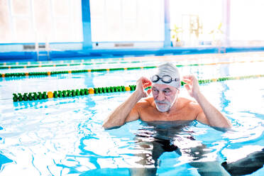 Senior man in an indoor swimming pool. Active pensioner enjoying sport. - HPIF20175