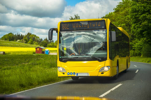 Gelber Bus, der sich auf der Straße in der Nähe der Wiese bewegt - FRF01020