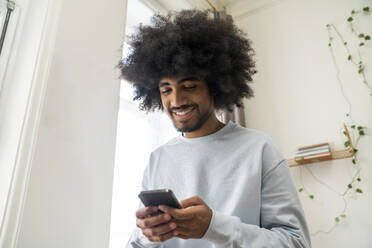 Lächelnder Mann benutzt Smartphone zu Hause - VPIF08167