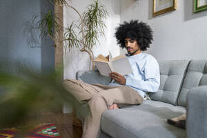 Mann liest ein Buch auf dem Sofa zu Hause - VPIF08207